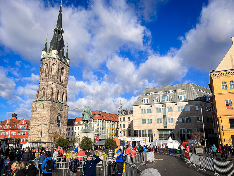 Runners and spectators gather at the market square in Halle before the start of the Central German Marathon. The iconic Red Tower, a landmark of the city, stands in the background.