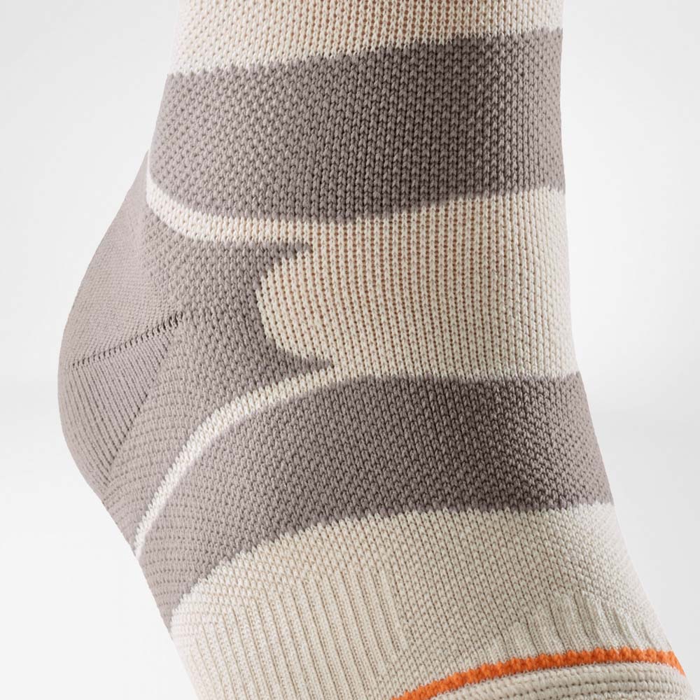 Close-up view of the Outdoor Compression Ankle Support in sandstone color. The image highlights the lateral stabilization zone and the structured knit design that supports the ankle during hiking and uneven terrain.