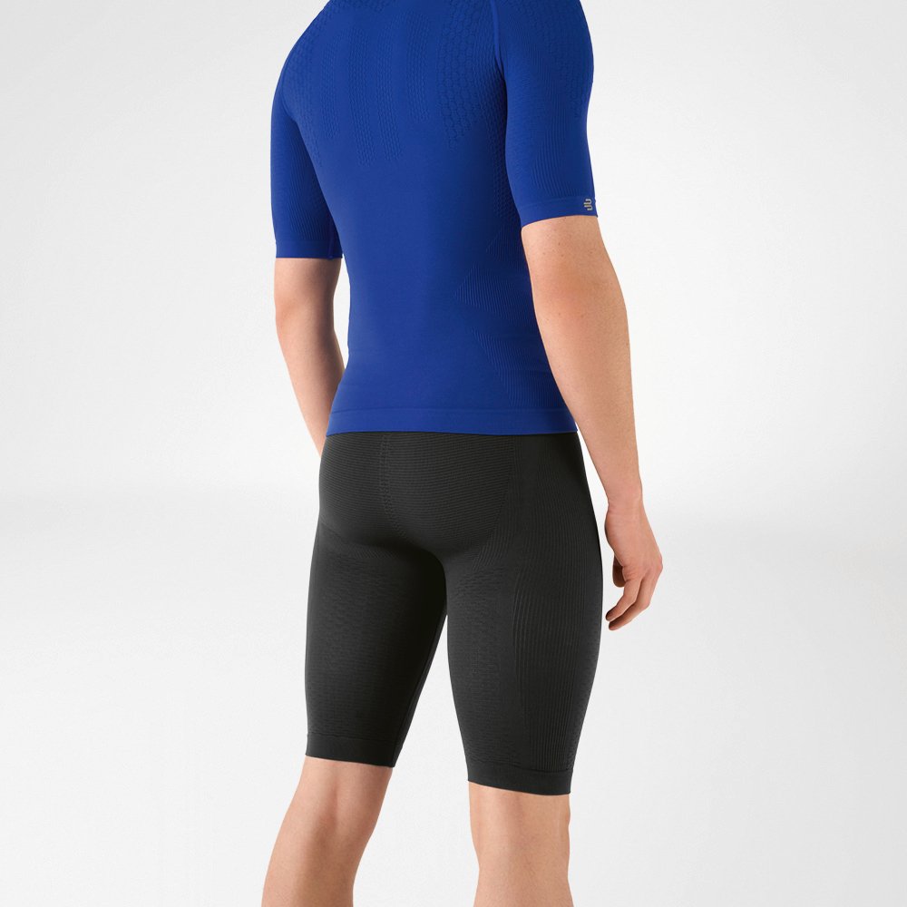 The man is wearing a tight-fitting blue shirt that emphasises his upper body and knee-length, navy blue, tight-fitting sports trousers that hug his lower body.