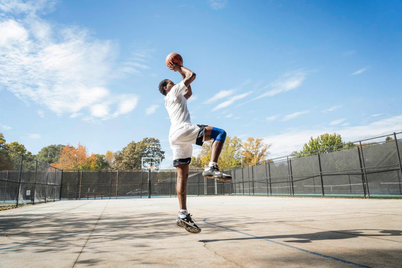Basketball players jump on a street court for the throw from hands with the ball over the head, bent into the other, show the other vertically downwards