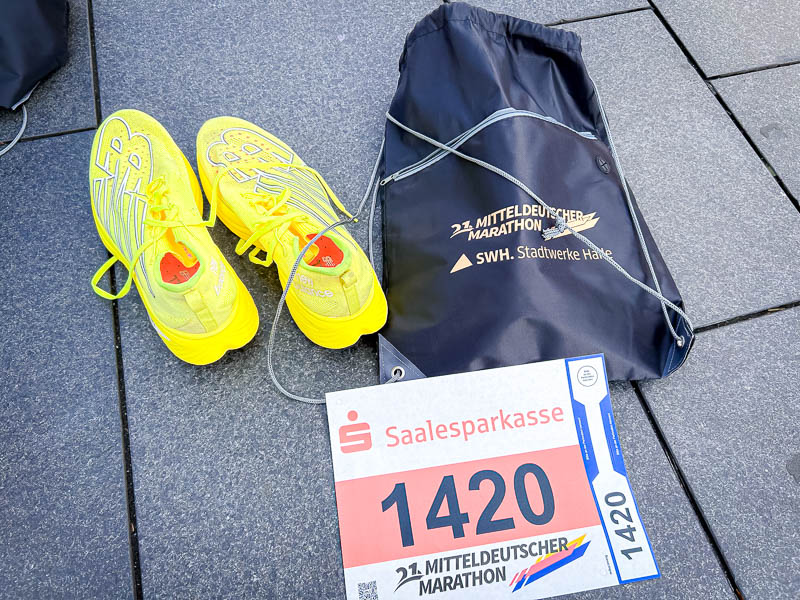 Race day at the half marathon: Yellow running shoes next to the bib number and a sports bag for the 21st Mitteldeutscher Marathon, ready to go.