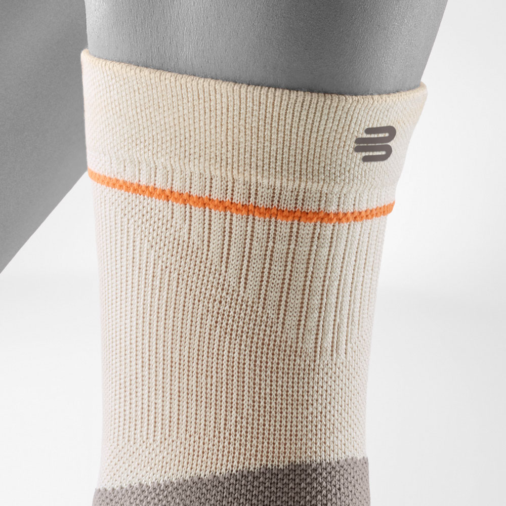 Detailed view of the upper cuff of the Outdoor Compression Ankle Support in sandstone. The close-fitting ribbed structure and subtle Bauerfeind Sports logo ensure a secure fit during long hikes.