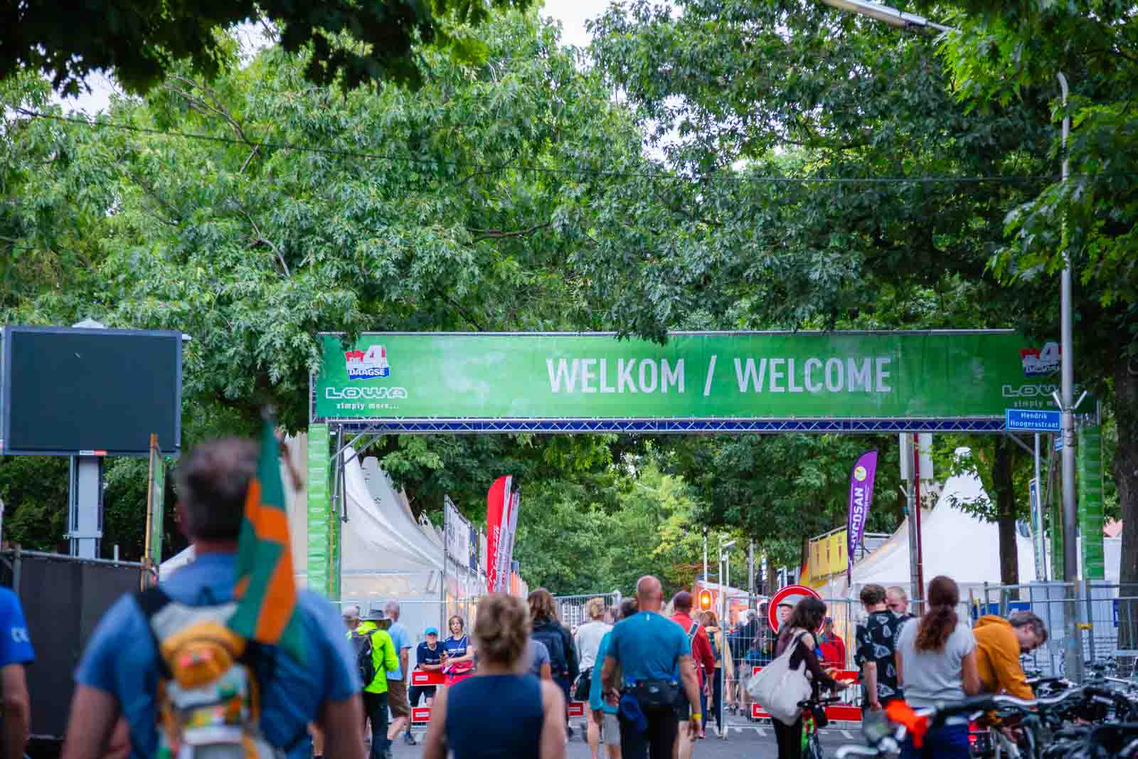 Entrance to the 4Daagse event in Nijmegen with a green “Welkom / Welcome” banner and many walkers heading to the start area.