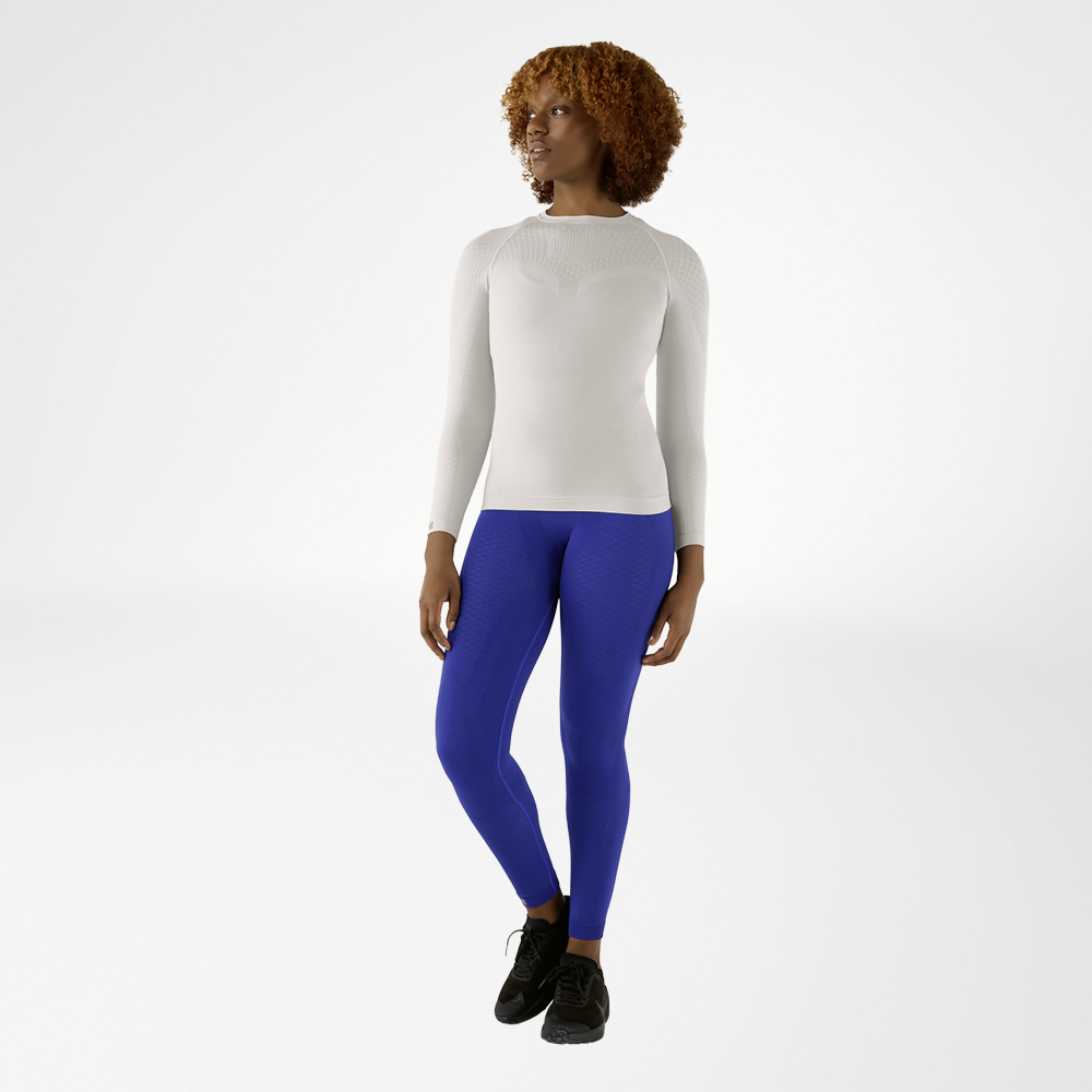 Woman in a silver-grey, close-fitting long sleeve shirt and blue compression pants, front view