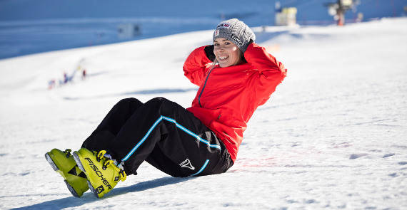 Ski runner in a red jacket makes a sit-up in the snow