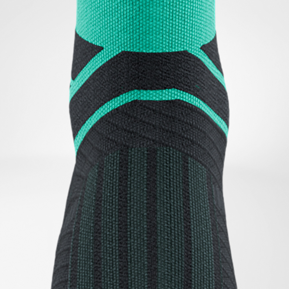Close-up of the instep area of a green Run Performance Midcut Sock. The woven line patterns highlight the compression zones around the ankle, providing additional support during running.
