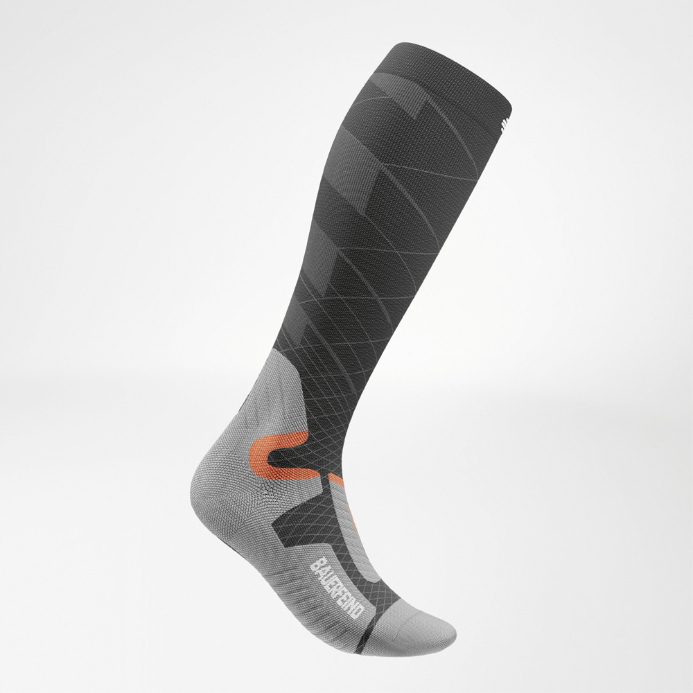 Maximum power for your top performance on the slopes Side view of a knee-high Bauerfeind Sports Ski Performance sock in anthracite, grey, and orange. The compression sock features a dynamic line design and an anatomically shaped foot.