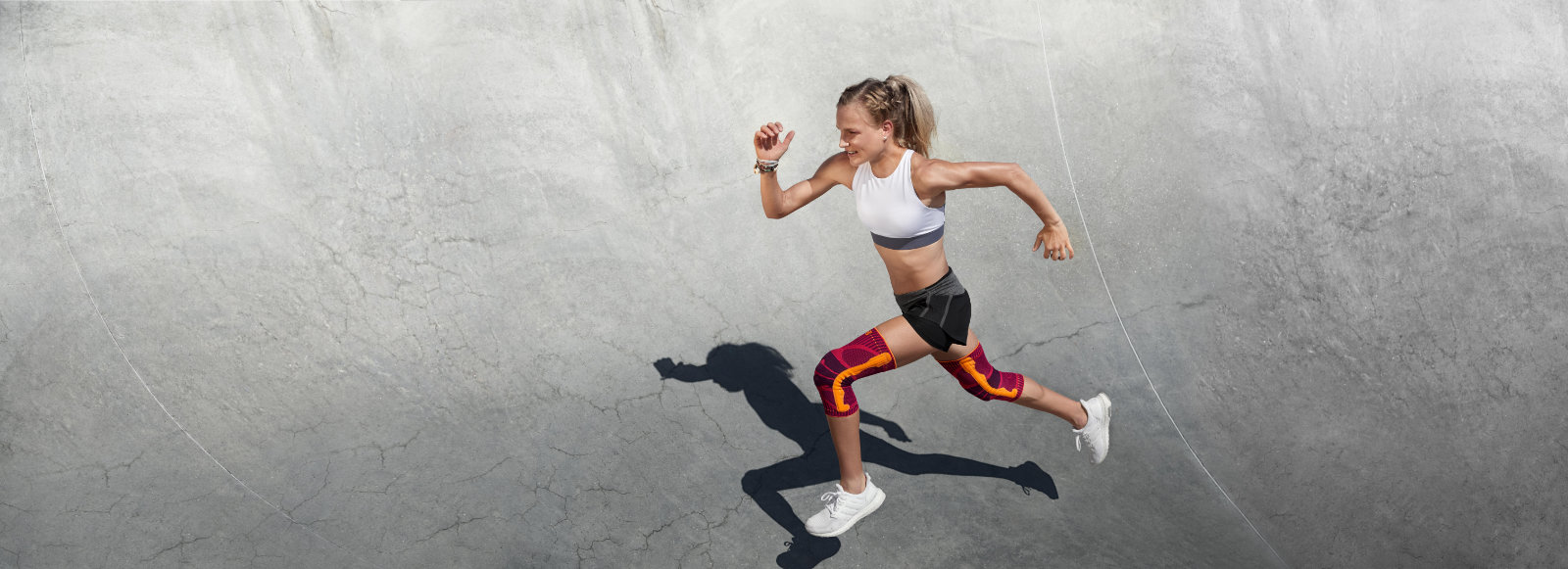 Pink power! Our Knee Support can also set great color accents for your run Woman in summer running clothes and with pink kneeboard runs over a concrete halbrund