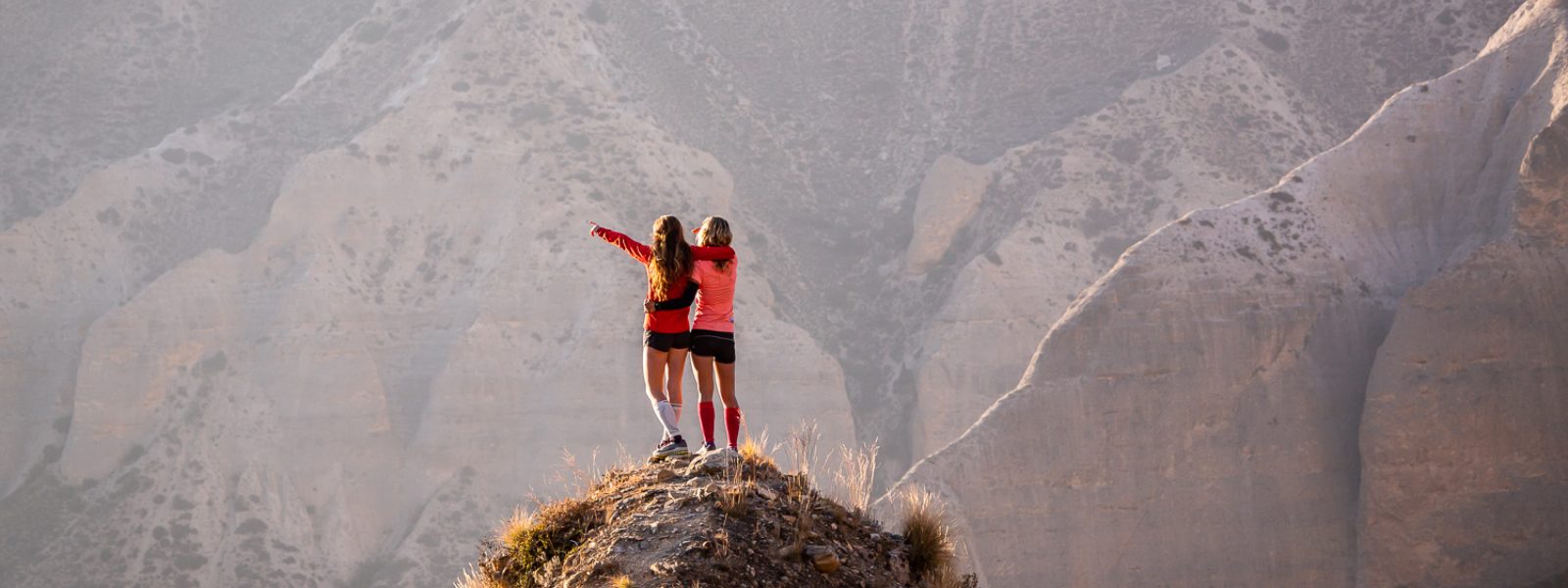 Two women cheer on a mountain summit