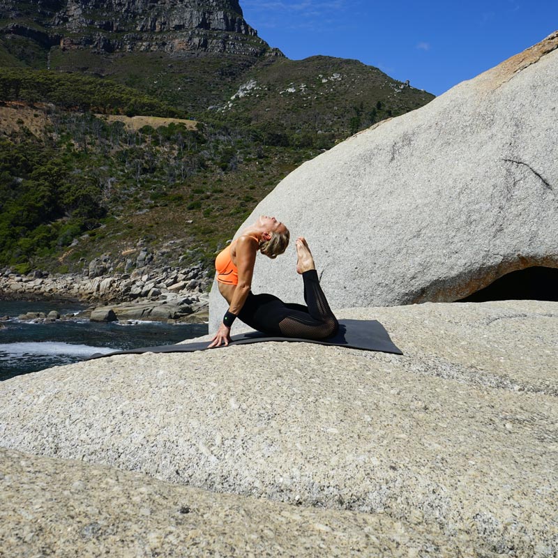 Woman in the Königskobra pose in the hollow cross her head touches the tips of the toe