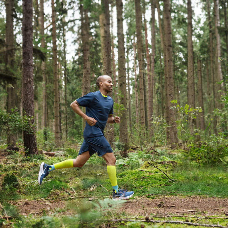 Runner runs through a forest wearing compression stockings A runner is running quickly through a dense forest wearing compression socks