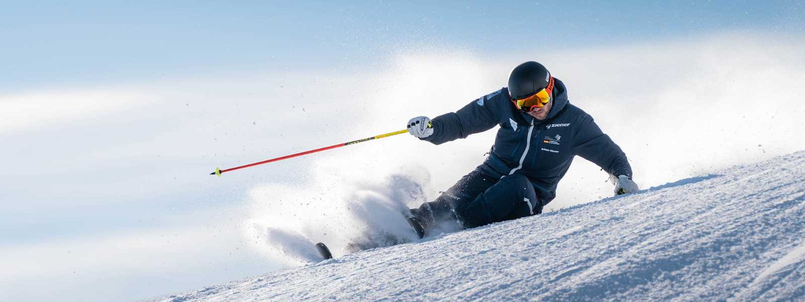 Skiers in a dark suit in an extreme incline on the departure