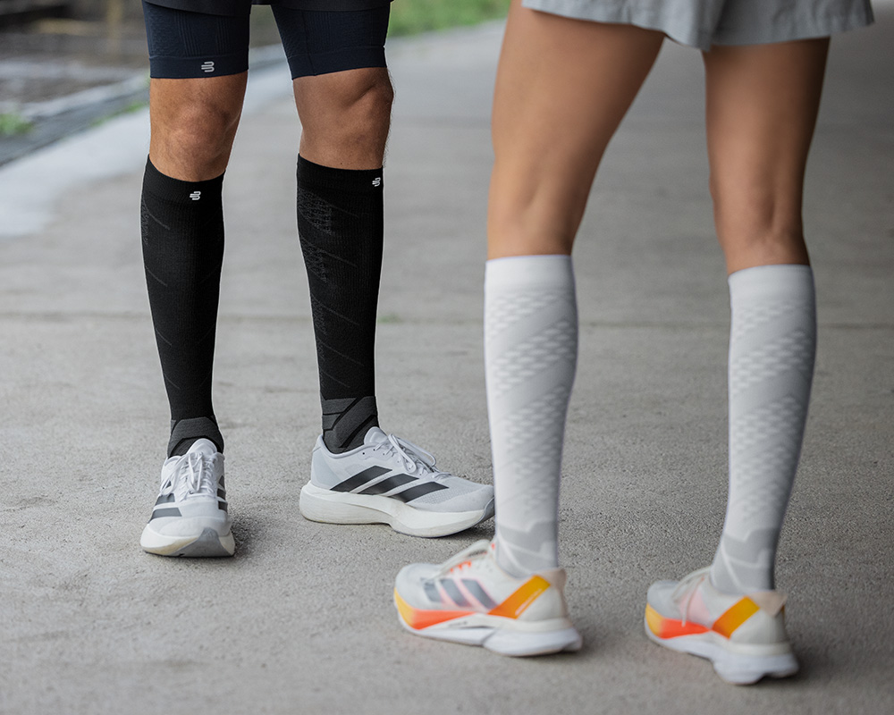 Lower leg of a runner in close -up with blue patterned running socks on a concrete surface
