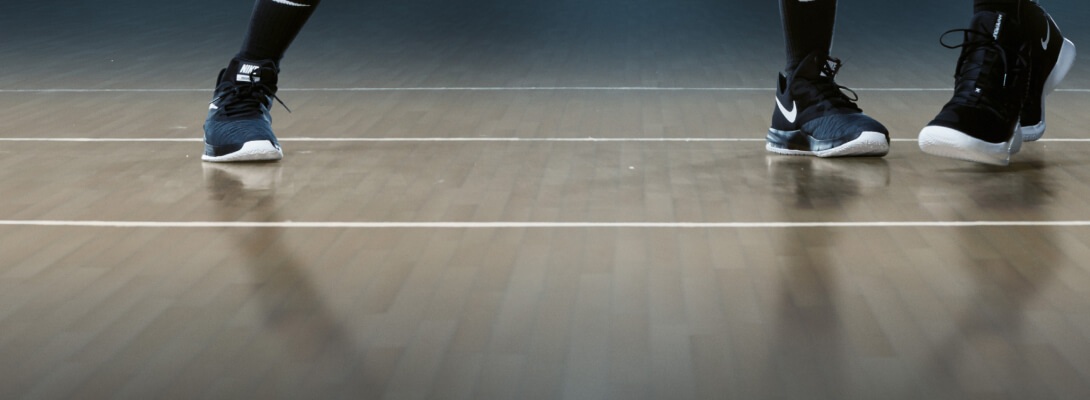 View of the floor of a basketball hall and the feet of two players