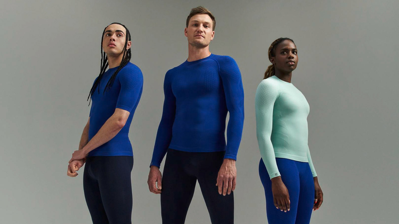 Three athletes in sportswear with compression shirts and compression pants in front of a gray background.