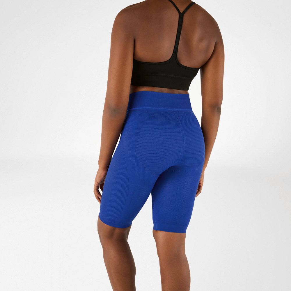 Woman photographed from behind in a black sports bra and knee-length, navy blue compression leggings.