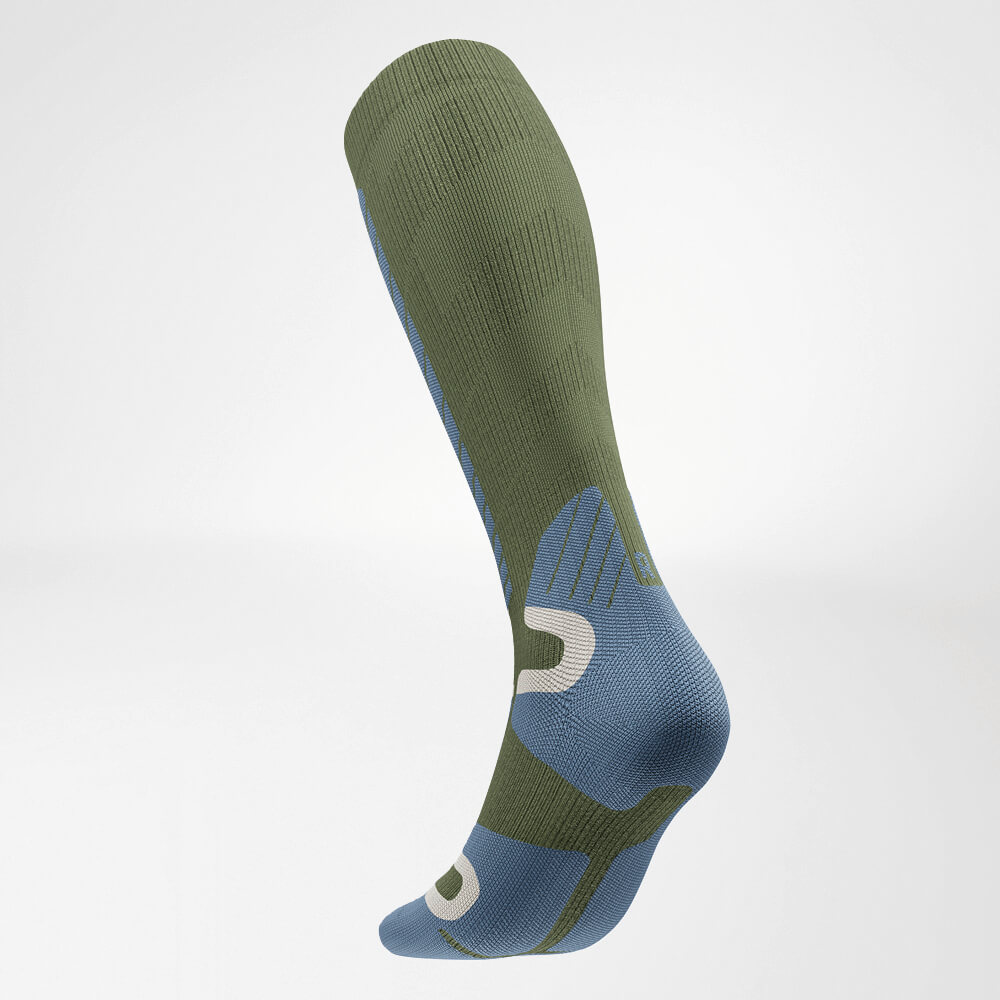 Angled rear view of a green knee-high ski compression sock with structured knit design for optimal support and comfort while skiing.