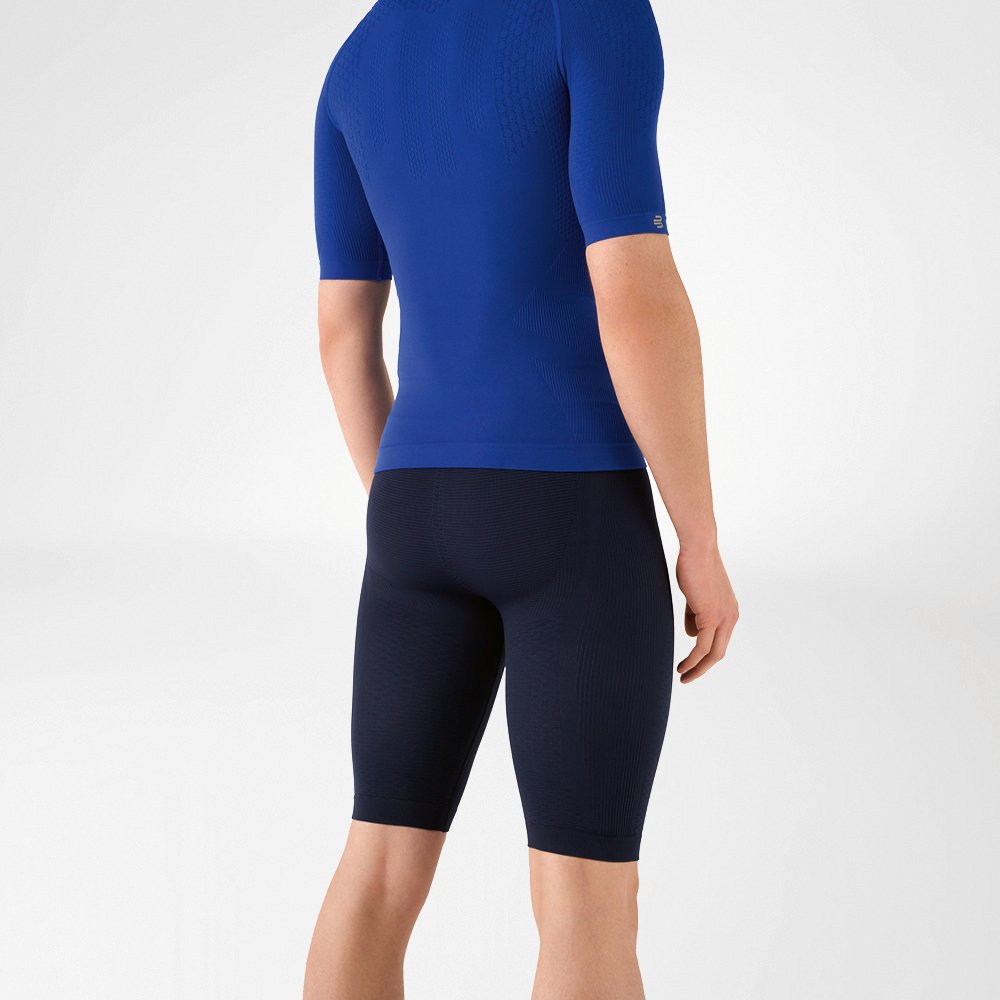 The man is wearing a tight-fitting blue shirt that emphasises his upper body and knee-length, navy blue, tight-fitting sports trousers that hug his lower body.
