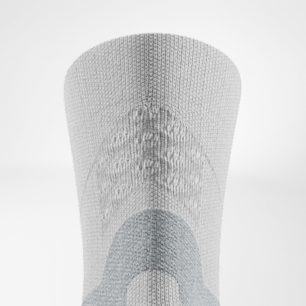 Close-up of the back of the white Run Performance Midcut sock: grey Achilles tendon comfort zone, knitted 3D dots at the cuff, and supportive knit zones along the calf.