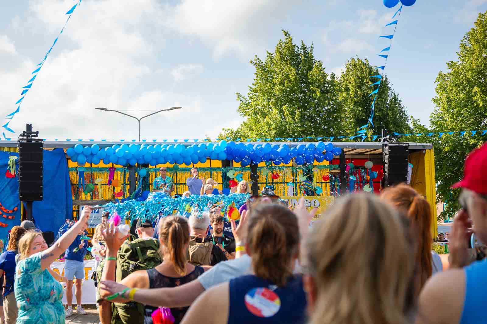 Colorfully decorated float with blue balloons and cheering spectators at the 4Daagse in Nijmegen.