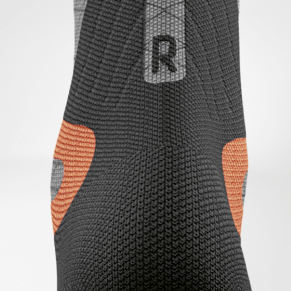 Stable in every turn – right heel with extra padding Detailed view of the right women's ski compression sock by Bauerfeind. Visible are the orange heel pads and black knit for precise in-boot support.