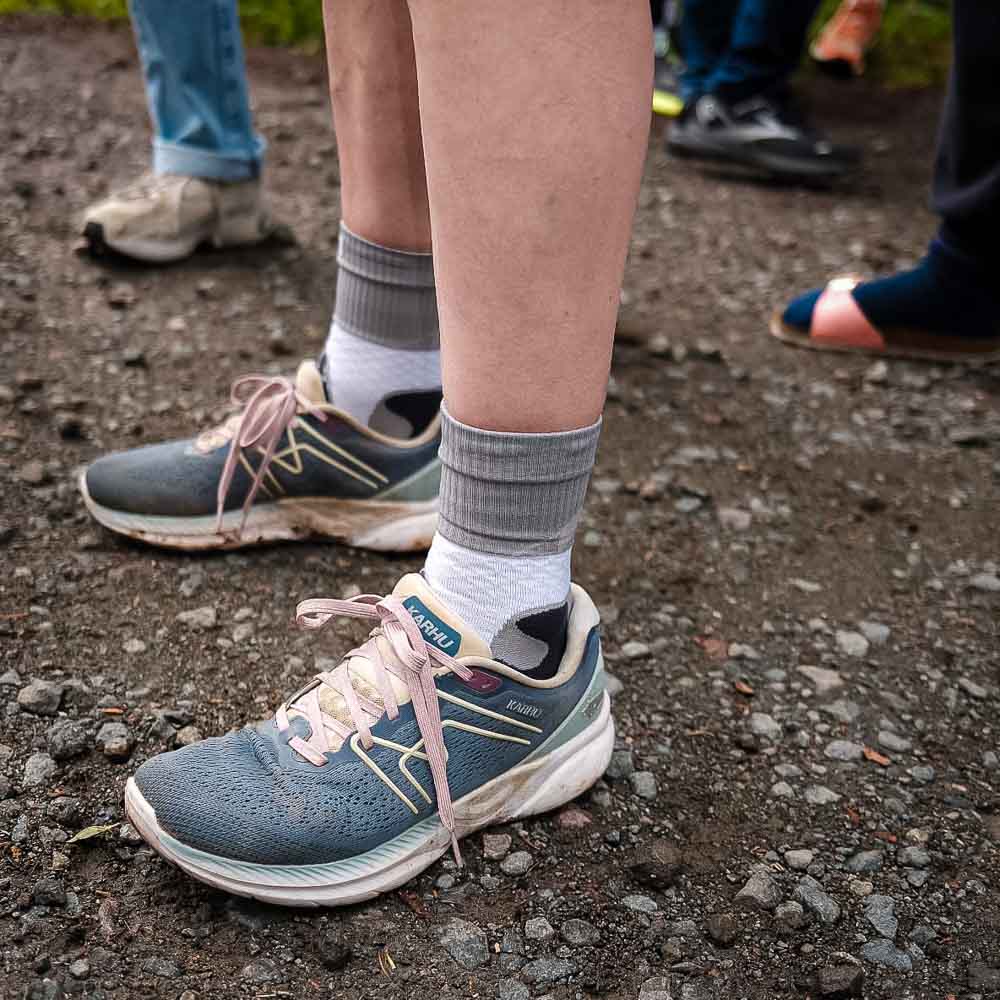 The legs and shoes of a woman wearing the Bauerfeind Trail Run Mid Cut Socks