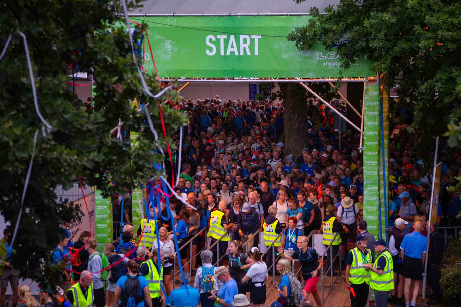 Participants of the 4Daagse event in Nijmegen gather at the crowded start area under a large green banner reading “START”.