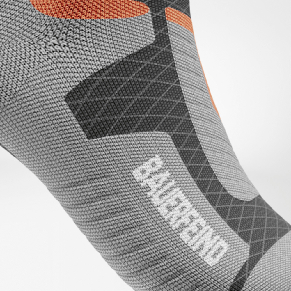 Performance down to your toes! Close-up of the foot section of the sock with grey, orange and black reinforcements and the BAUERFEIND logo on the instep.
