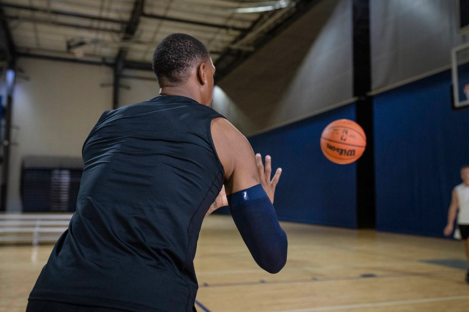 Basketball players with a blue Armsleeve in sports hall awaits a ball that is thrown at him by another player