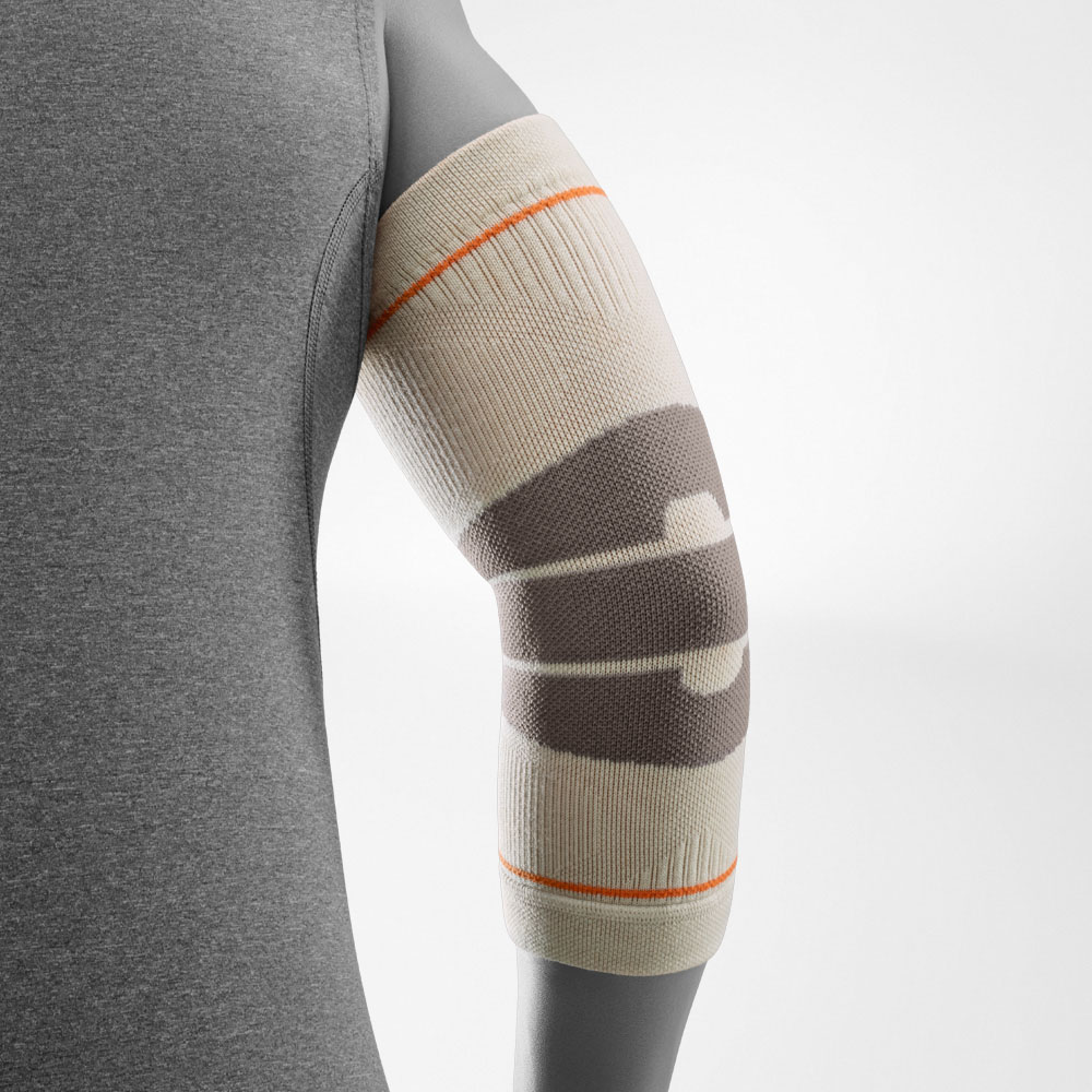 A hiker wearing the Outdoor Compression Elbow Support in sandstone on the right arm. The elbow support provides even compression around the joint, offering stability and support during outdoor activities such as hiking or trekking.