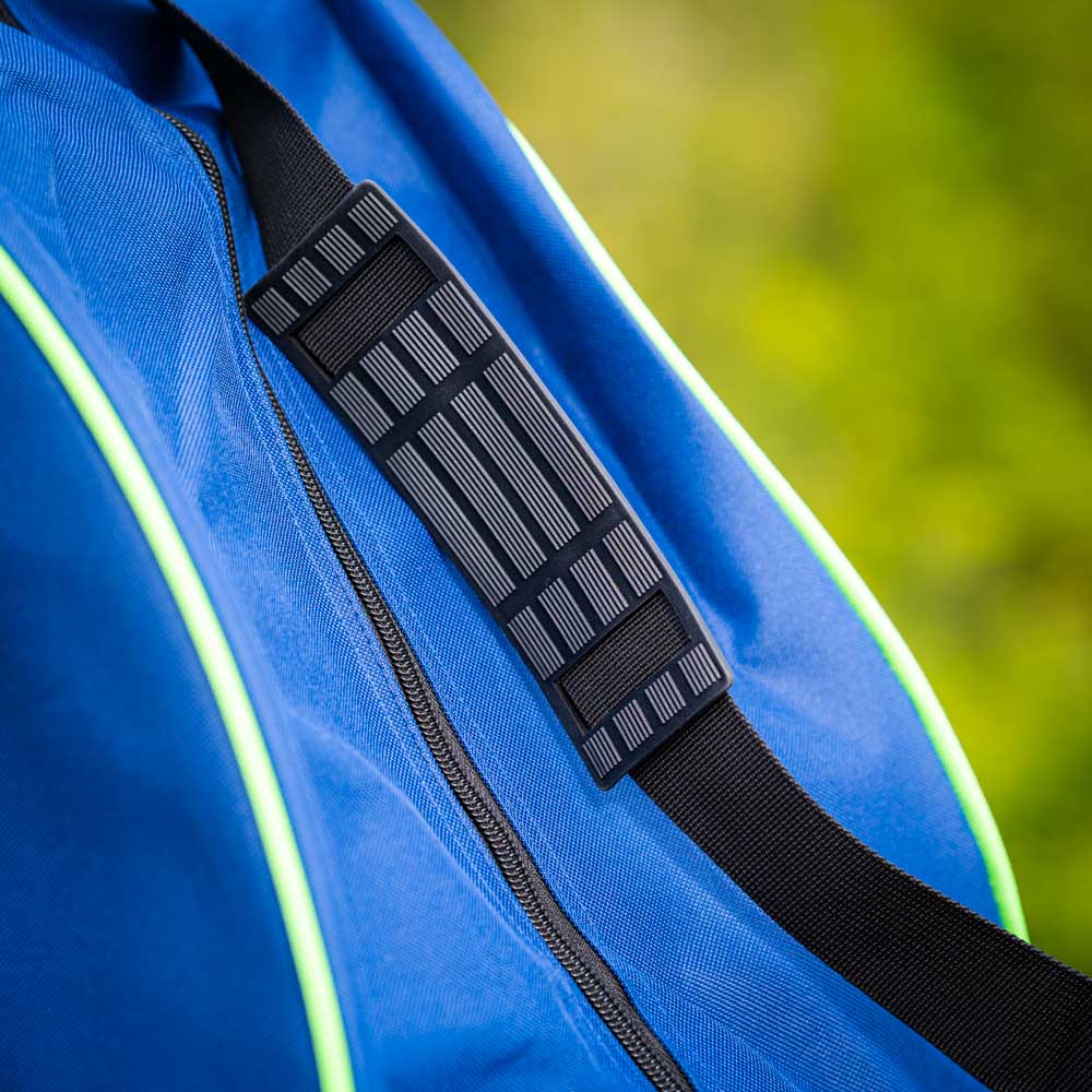 Close-up of a padded black shoulder strap on a blue bag with green accents. The strap has a textured surface for added grip.
