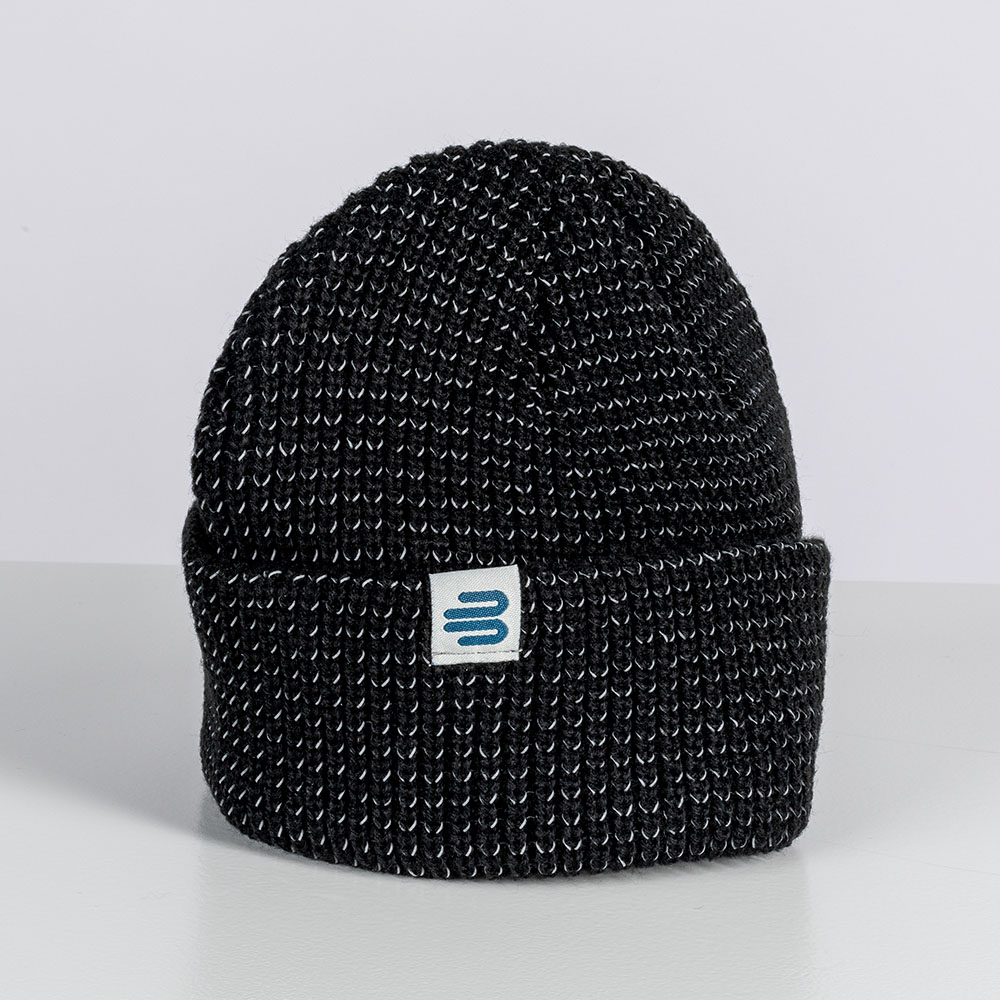 A black knitted beanie by Bauerfeind Sports with an embroidered logo placed on a light background in the studio. The beanie has a thick texture and a folded cuff.