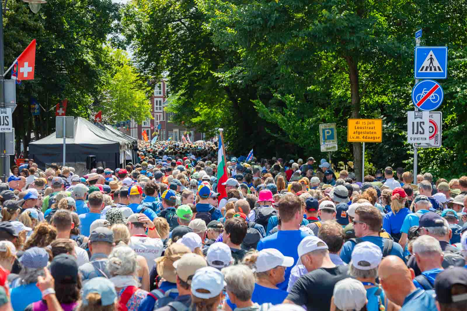 Large crowd of walkers during the 4Daagse in Nijmegen, moving through the streets with flags, signs and a summer atmosphere.