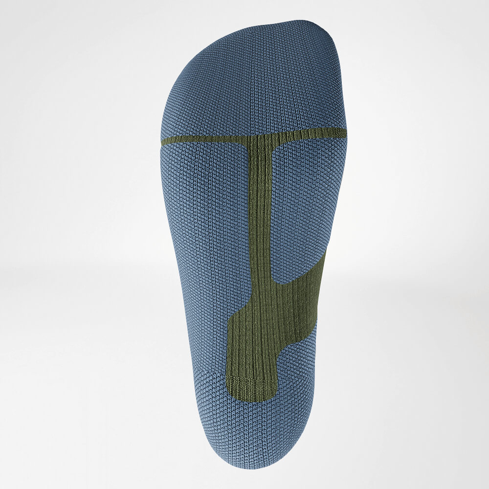 Close-up of the sole of a green ski compression sock with ergonomic knit design for stability and cushioning during intense sports activities.