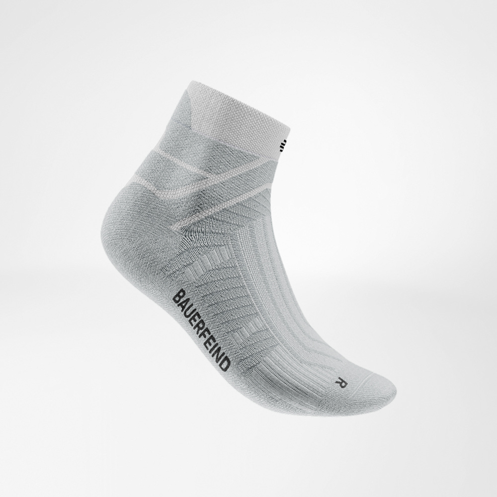 Leicht und frisch – die weiße Socke in Szene gesetzt. White Run Performance Low Cut sock by Bauerfeind in a side view, showing the knit pattern, breathable zones, and Bauerfeind lettering on the outside.