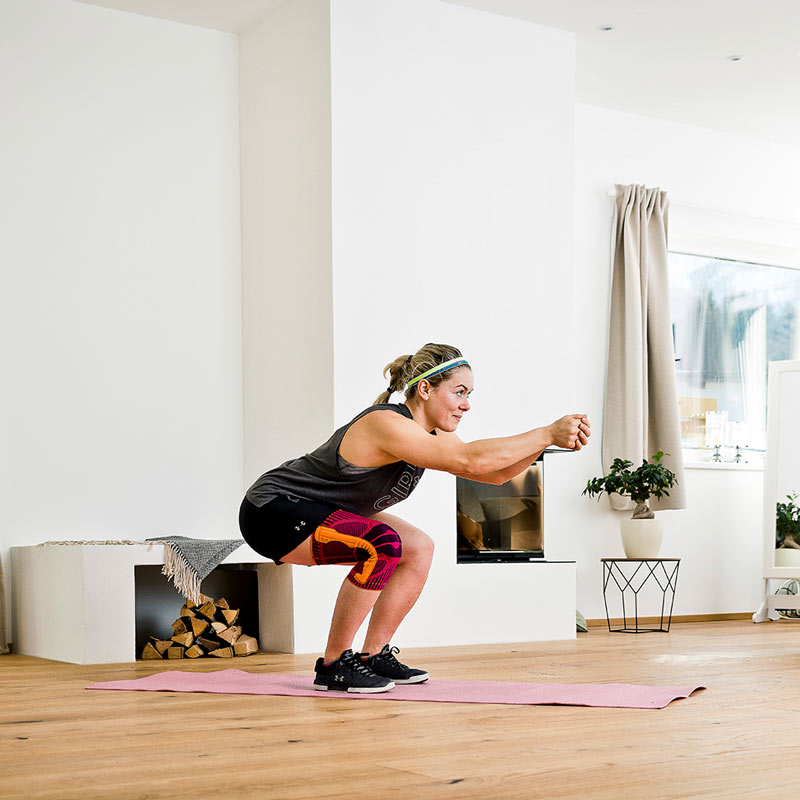 Woman with a kneeze simulates the ski descendant position in a fireplace room, straight arms move forward with interrogated hands