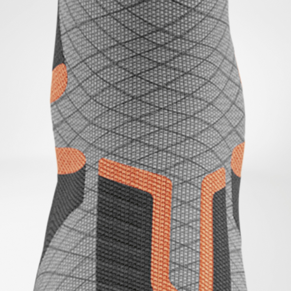 Built for impact and drive – padded shin protection Frontal close-up of the shin area of the women's ski compression sock featuring U-shaped orange padding and diamond knit for impact protection.