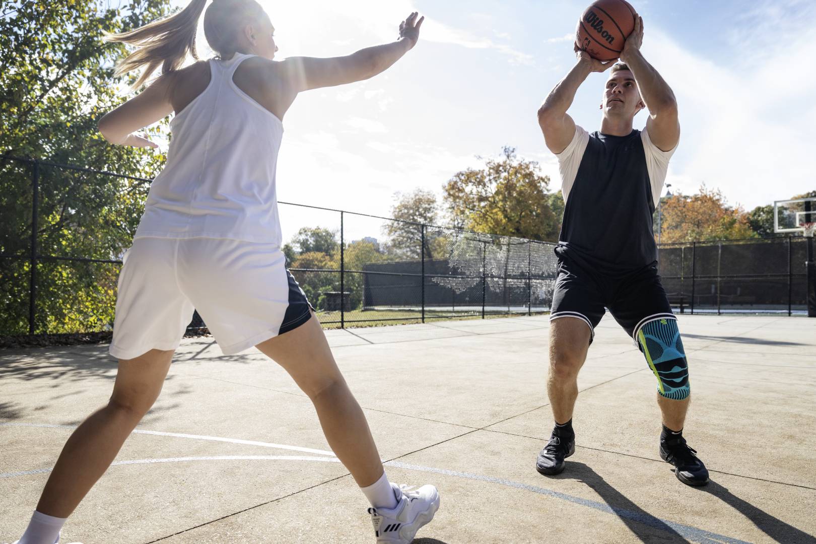 Basketball players with a kneeze starts with a streetball while his opponent tries to block him