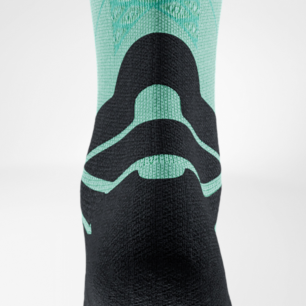 Back view of a green and black running sock by Bauerfeind Sports, focusing on the Achilles tendon. The special padding is clearly visible and protects during sports.