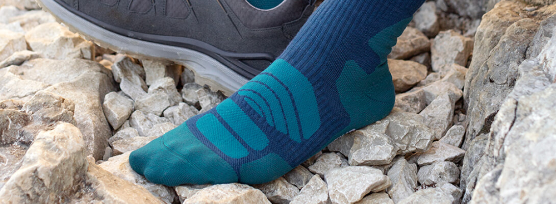 Foot in a merino hiking socks on a stony surface