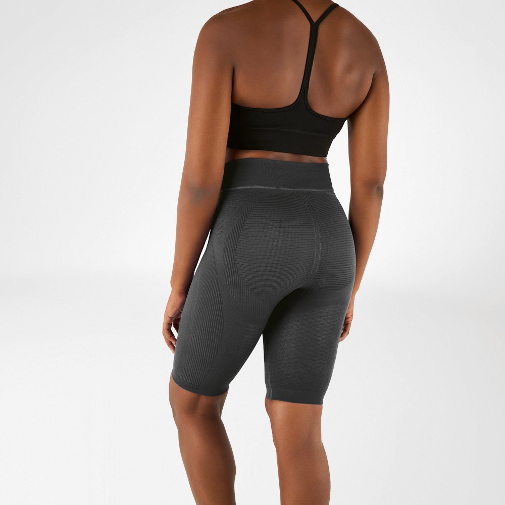 Woman photographed from behind in a black sports bra and knee-length, anthracite-coloured compression leggings.