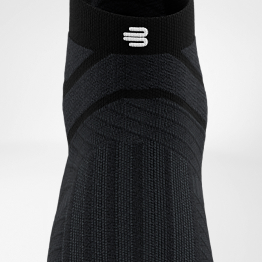 Black Run Performance Low Cut Sock from Bauerfeind in a frontal view, highlighting the functional knit pattern on the instep and the elastic cuff with white logo.