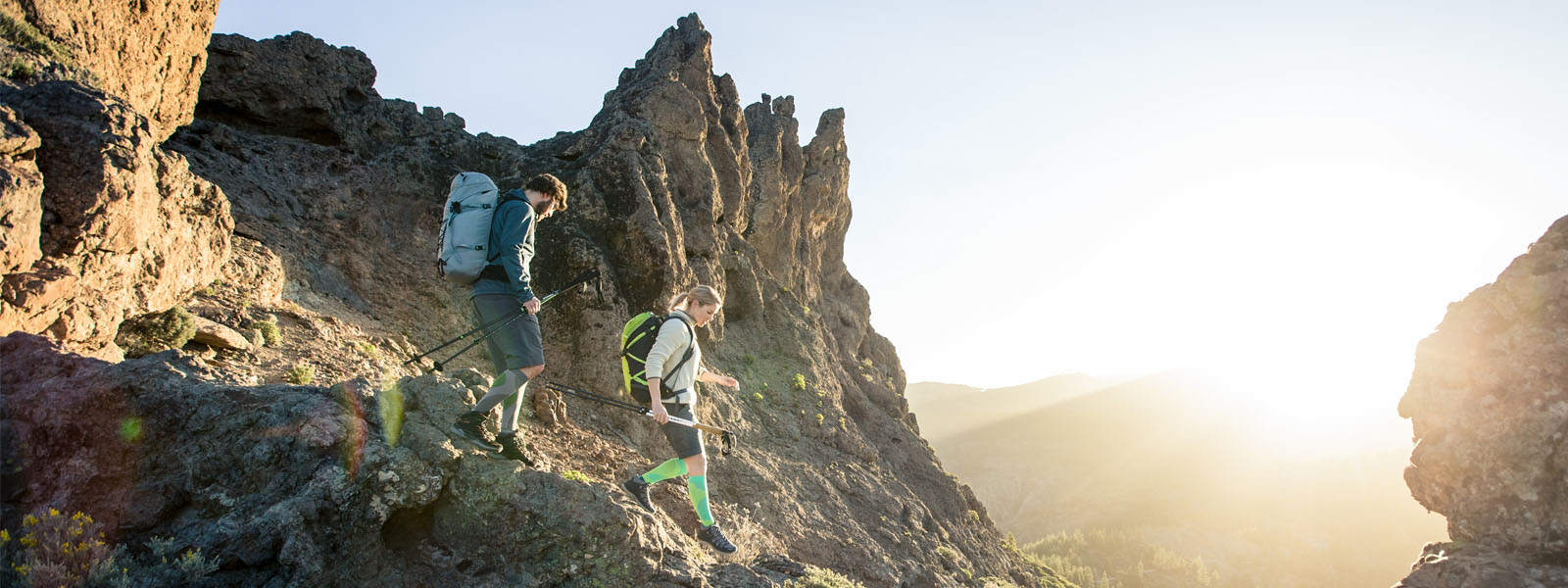 Hiking joy until sunset: our outdoor performance compression socks Two hikers with long hiking socks go down a steep path on a mountain at dusk