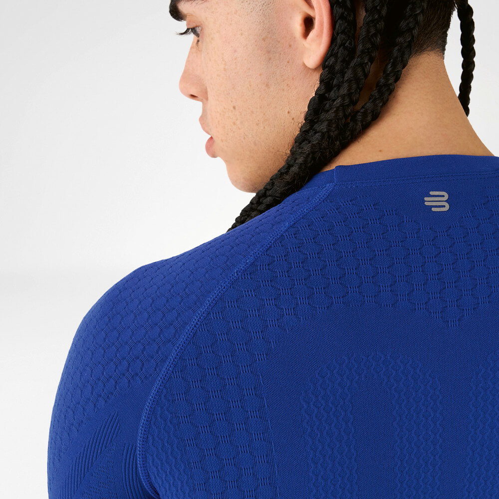 Back view of an athlete in a blue compression shirt with textured fabric and braided hair.
