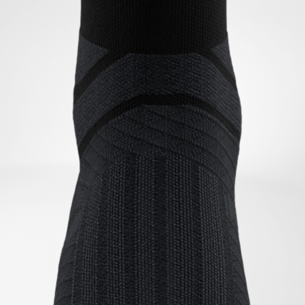 Rear view of the black Run Performance Midcut Sock with reinforced Achilles tendon comfort zone. The dark knit design emphasizes ergonomic padding.