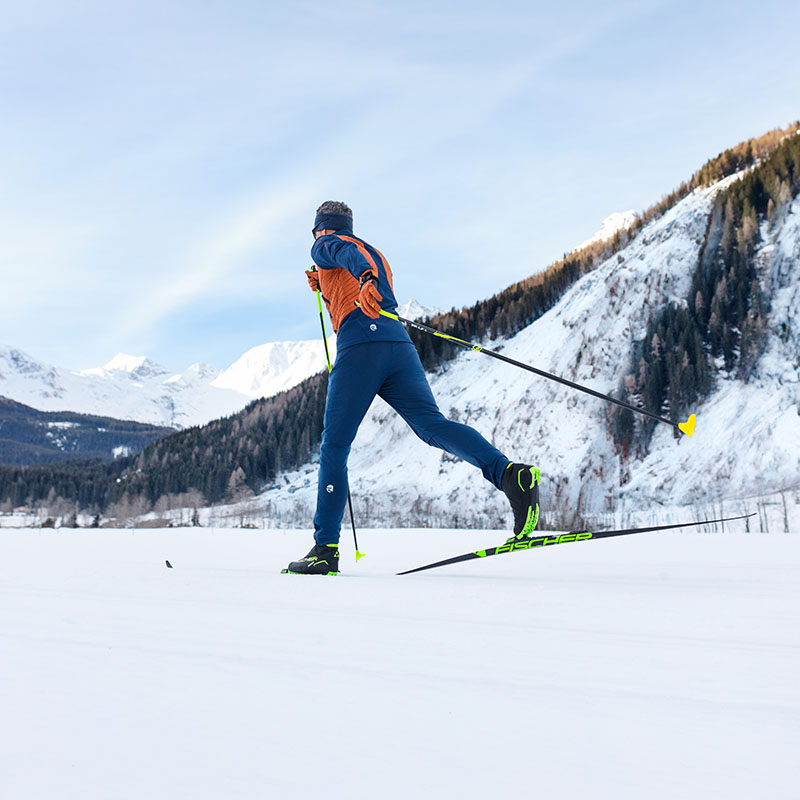 You can see a man cross-country skiing in the Alps