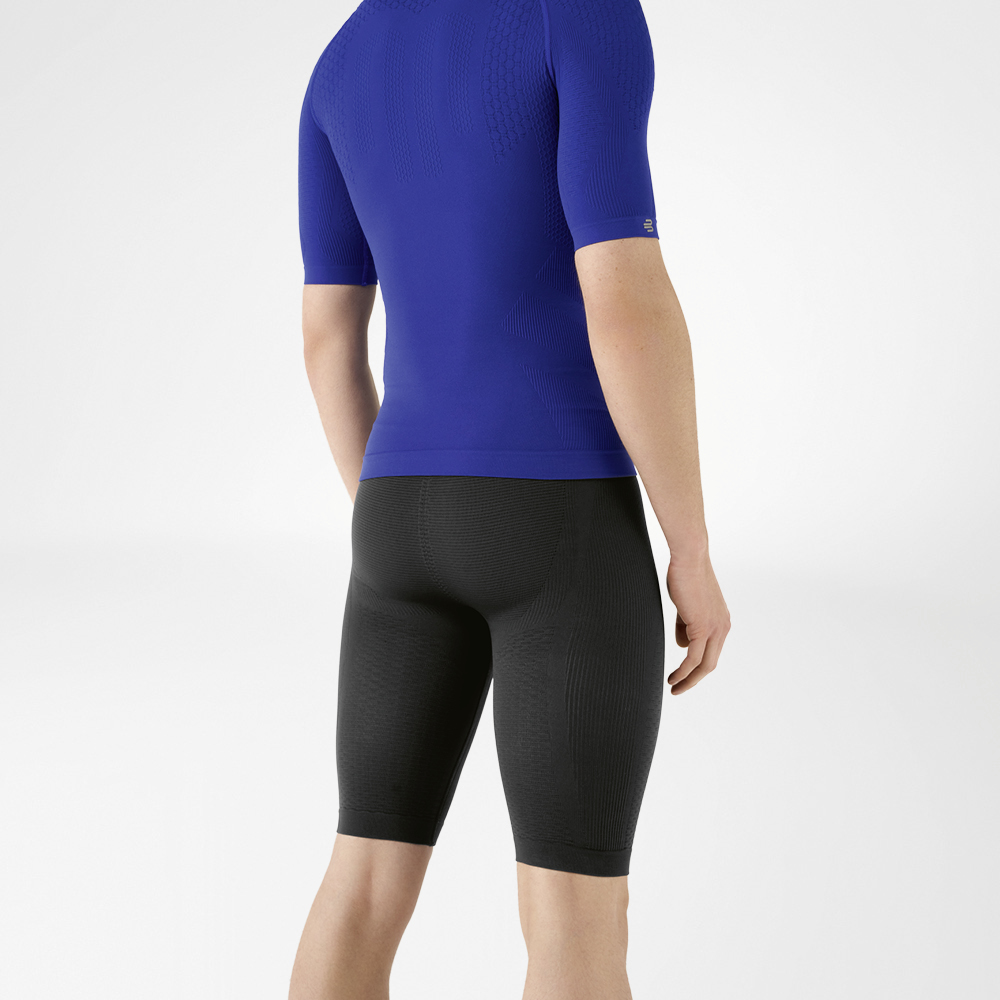 The man is wearing a tight-fitting blue shirt that emphasises his upper body and knee-length, navy blue, tight-fitting sports trousers that hug his lower body.