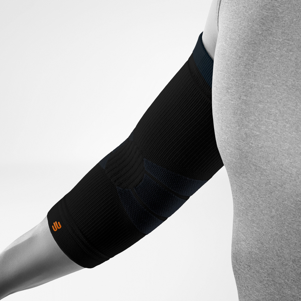 Angled view of the black Outdoor Compression Elbow Support on the forearm and elbow. The compression sleeve highlights anatomically shaped support zones and the integrated logo near the lower edge.