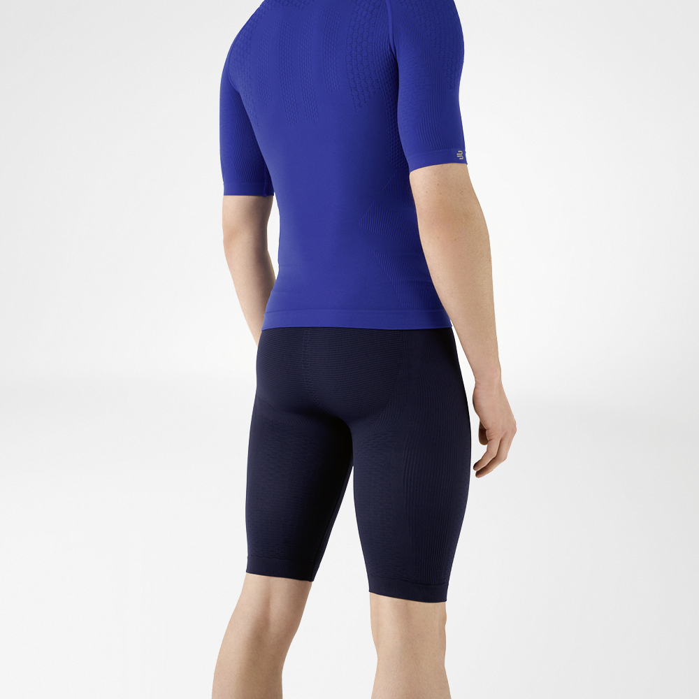 The man is wearing a tight-fitting blue shirt that emphasises his upper body and knee-length, navy blue, tight-fitting sports trousers that hug his lower body.