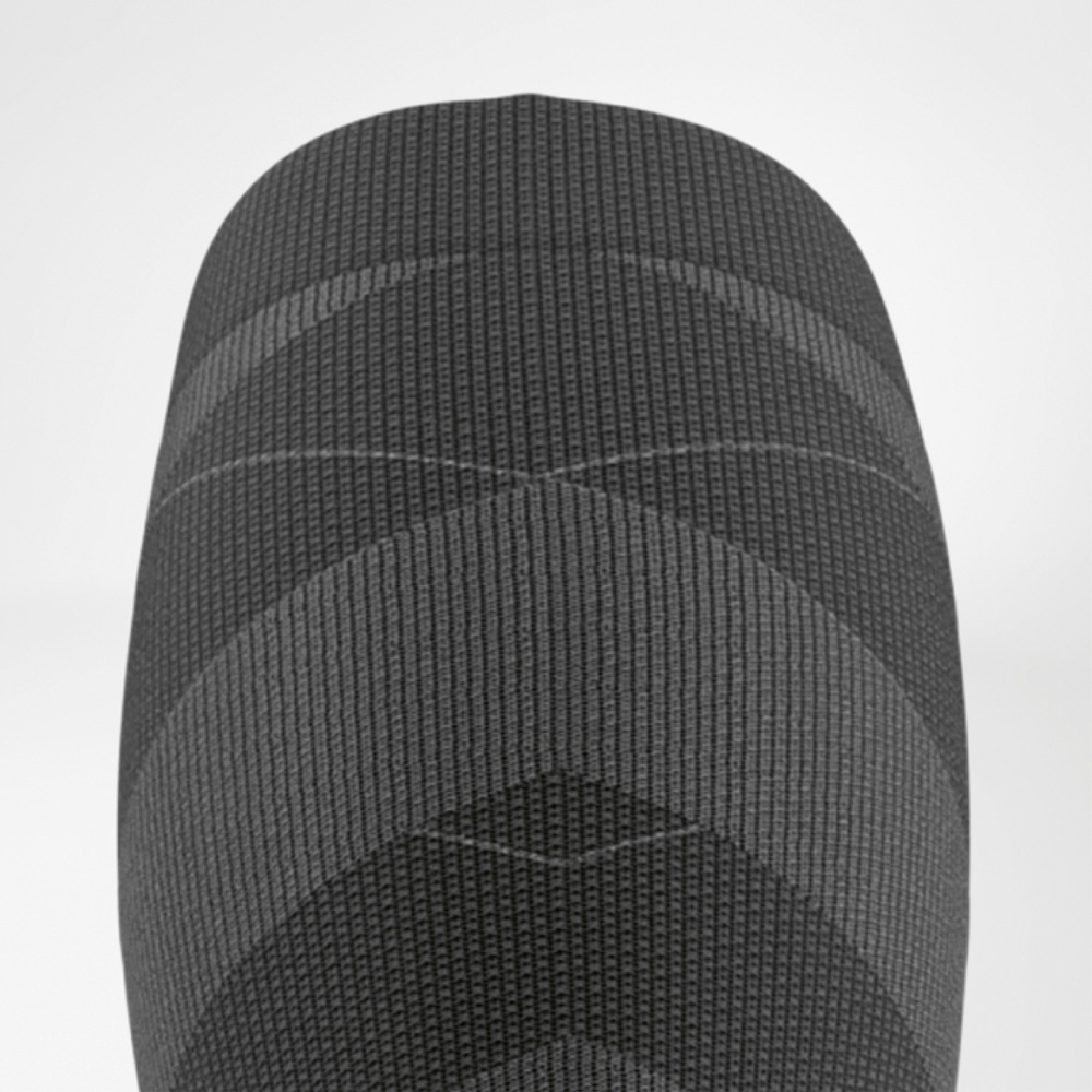 Locked in at the top! Close-up of the upper cuff of the ski performance sock in black and grey with fine ribbed structure for optimal grip on the calf.